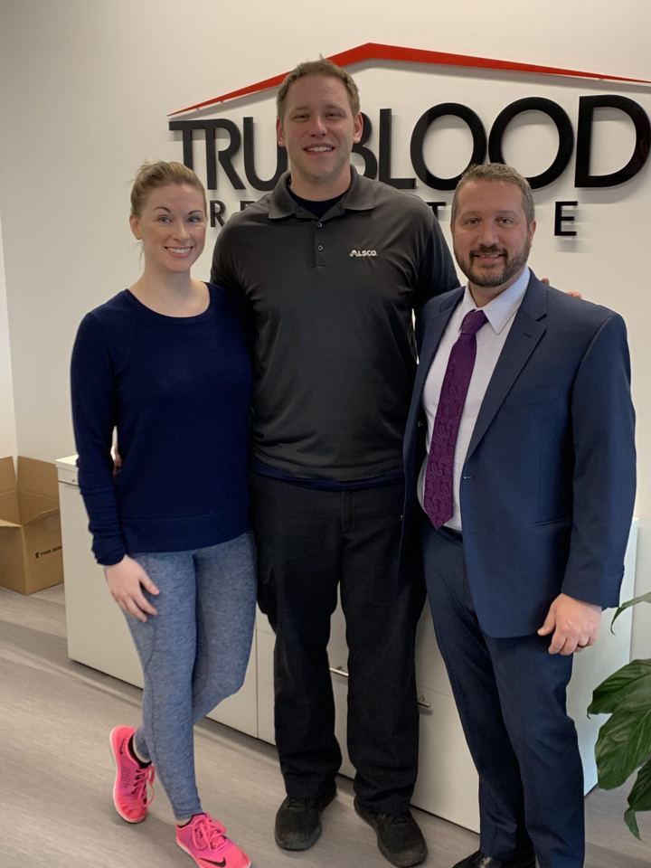 Wes with two people standing in front of the Trueblood Real Estate sign