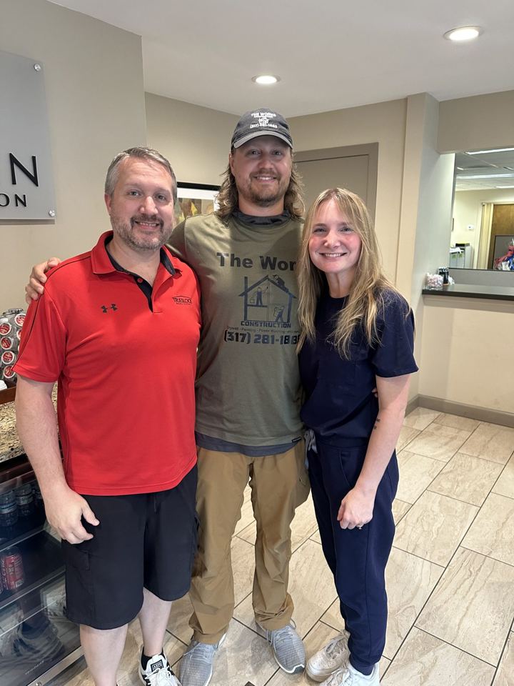 Wes with two people, one in a The Works Construction shirt, in a hotel-style lobby